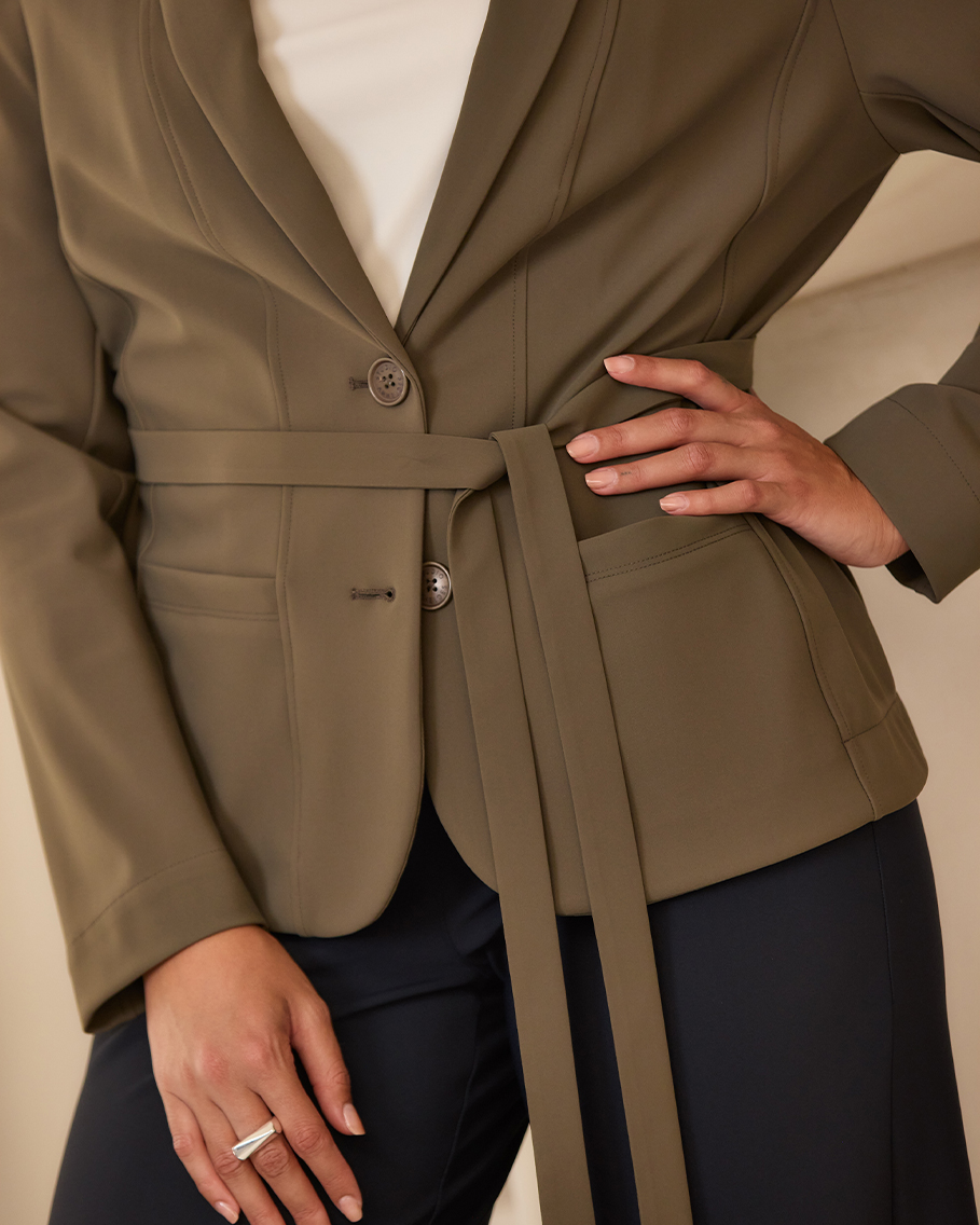 Detail van een olijfgroene @Work blazer van travelstof met ceintuur